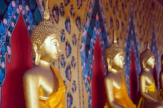 A row of seated Buddhas at the temple of Wat Arun in Bangkok, Thailand.  (Focus on far left Buddha)