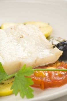 fillet of cod baked tomatoes zucchini black olives isolated