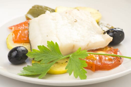 fillet of cod baked tomatoes zucchini black olives isolated