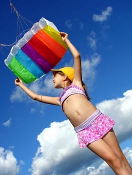 child starts flying kite against blue sky with clouds