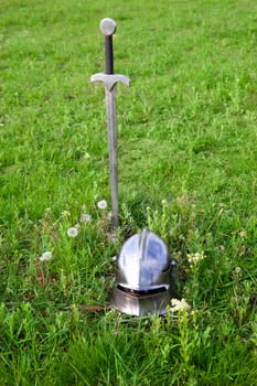 sword and helmet on the green grass