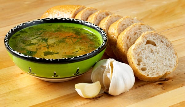 Soup, bread and garlic still life over wooden table