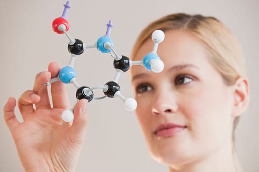 female chemist holding up molecules and looking at them