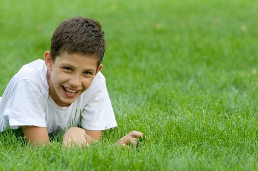 a boy is smiling on the green grass
