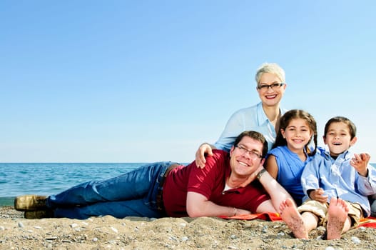 Happy family laying on towel at sandy beach