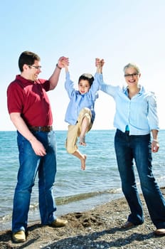 Portrait of parents lifting boy playfully at beach