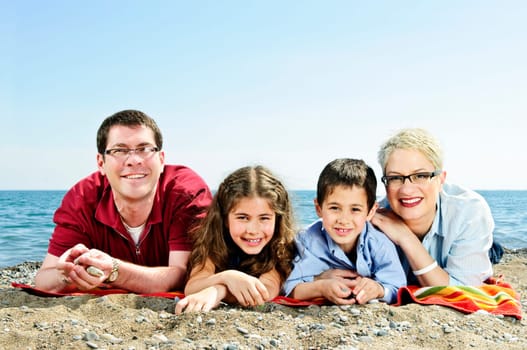 Happy family laying on towel at sandy beach