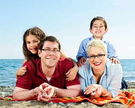 Happy family laying on towel at sandy beach