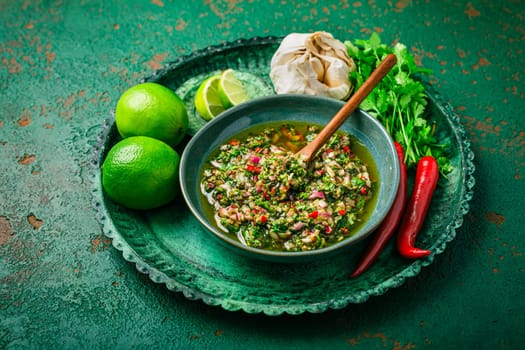 Raw homemade Argentinian green Chimichurri or Chimmichurri salsa or sauce made of parsley,  cilantro, chili, garlic, oregano, olive oil and red wine vinegar