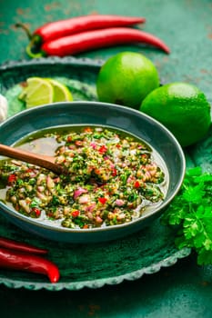 Raw homemade Argentinian green Chimichurri or Chimmichurri salsa or sauce made of parsley, cilantro, chili, garlic, oregano, olive oil and red wine vinegar