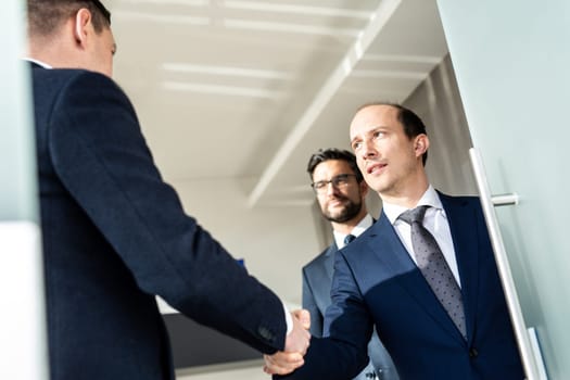 Group of confident business people greeting with a handshake at business meeting in modern office. Closing the deal agreement by shaking hands. Business and entrepreneurship success concept.