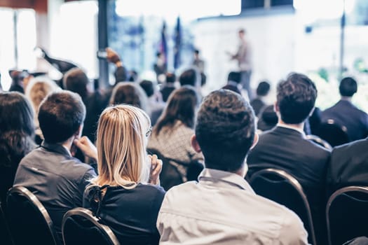 Speaker giving a talk in conference hall at business event. Rear view of unrecognizable people in audience at the conference hall. Business and entrepreneurship concept