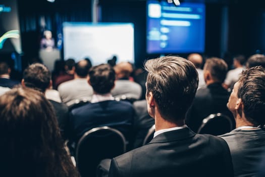 Speaker giving a talk in conference hall at business event. Rear view of unrecognizable people in audience at the conference hall. Business and entrepreneurship concept