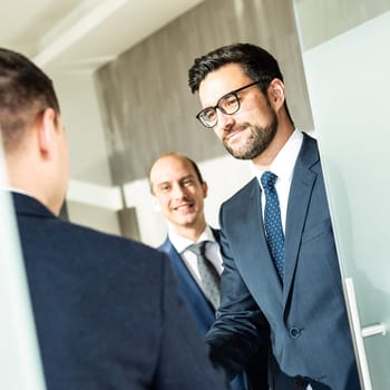 Group of confident business people greeting with a handshake at business meeting in modern office. Closing the deal agreement by shaking hands. Business and entrepreneurship success concept.