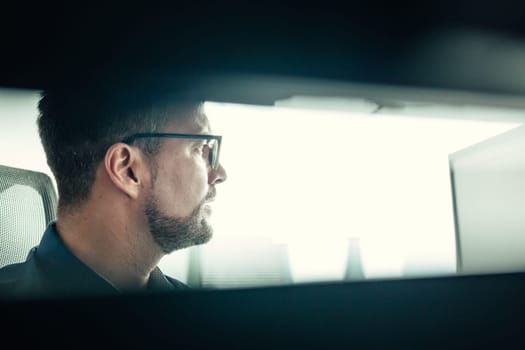 Male stock broker trading online watching charts and data analyses on multiple computer screens.