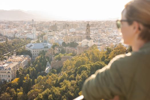 Bolnde female touris enjoying amazing panoramic aerial view of Malaga city historic center, Coste del Sol, Andalucia, Spain.