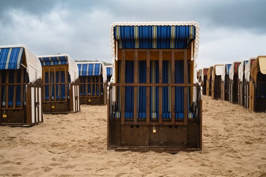 Roofed wicker beach chairs at the baltic sea beach, coast at the island of Usedom in Germany, storm and rain over the brackish water, high waves, storm warning