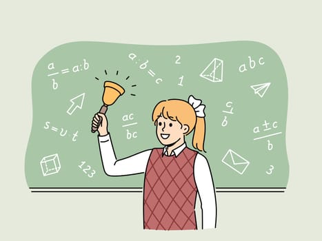 Girl elementary school student with bell stands near chalkboard with mathematical formulas and examples. Happy schoolgirl with bow on blond hair makes call, for concept back to school