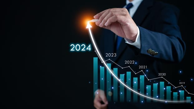 Stock trading. Finance. Investing. Growing business. Businessman in suit pointing with a pen at the tip of an arrow and a graph bar Represents business growth in 2024.