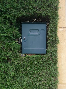 Exterior mailbox embedded by a thick hedge. Domestic garden concept