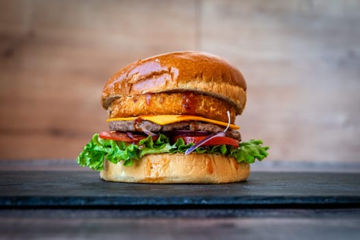 beef burger with sesame lettuce bun tomato cheddar cheese on black background