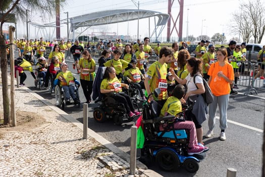 March 12, 2023 Lisbon, Portugal: people in sports clothes run a marathon - people with disability getting help at the stop. Mid shot