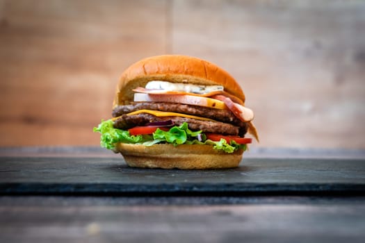 beef burger with sesame lettuce bun tomato cheddar cheese on black background