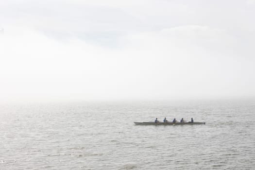 March 12, 2023 Lisbon, Portugal: Four people sailing on a canoe on a river on a foggy day. Mid shot