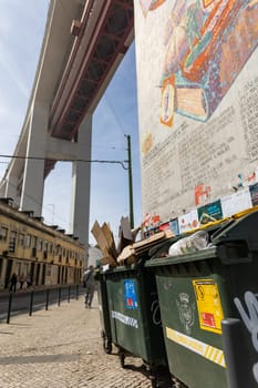 March 12, 2023 Lisbon, Portugal: trash cans painted with graffiti under the 25th of April Bridge. Mid shot