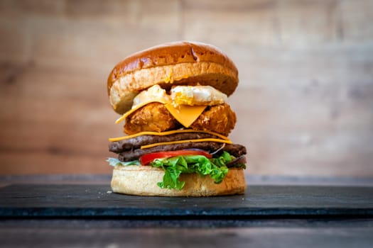 beef burger with sesame lettuce bun tomato cheddar cheese on black background