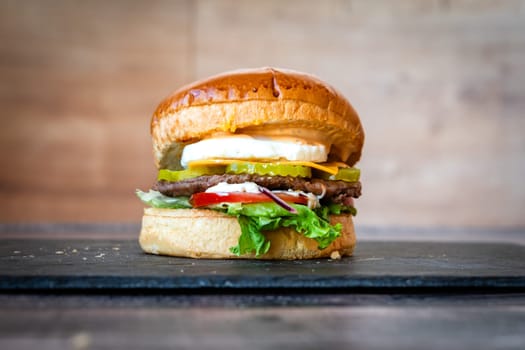 beef burger with sesame lettuce bun tomato cheddar cheese on black background