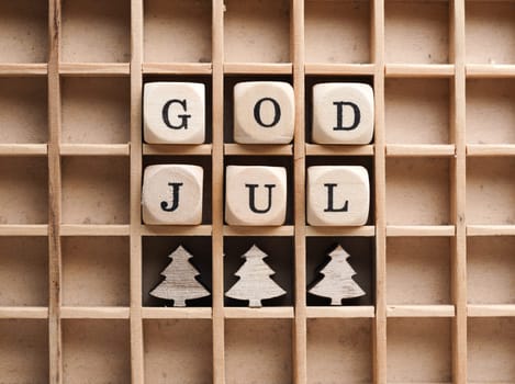 Small wooden blocks with the inscription God Jul, Scandinavian Merry Christmas, seasonal background with wooden tree shapes