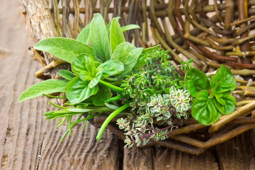 Freshly harvested herbs in a basket on wooden background