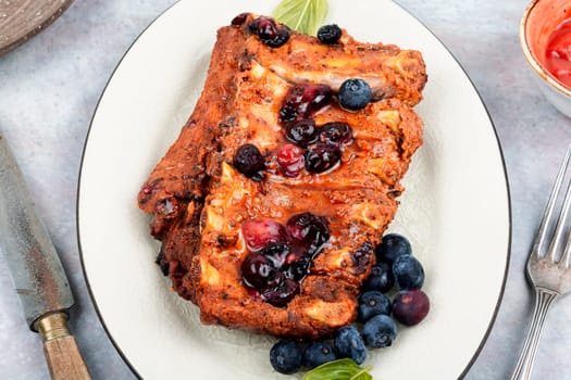 Fried pork ribs with blueberry sauce on a stone background