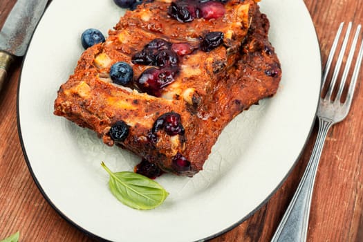 Fried pork ribs with blueberry sauce on a stone background