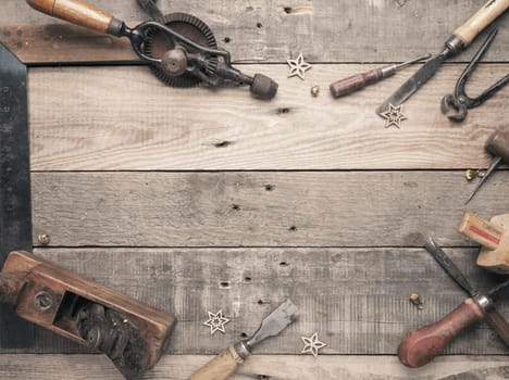 Vintage carpenter tools as a frame on a rustic wooden workbench with space for text, workshop concept