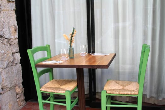 Outdoor table set for eating with two green chairs and rattan seats