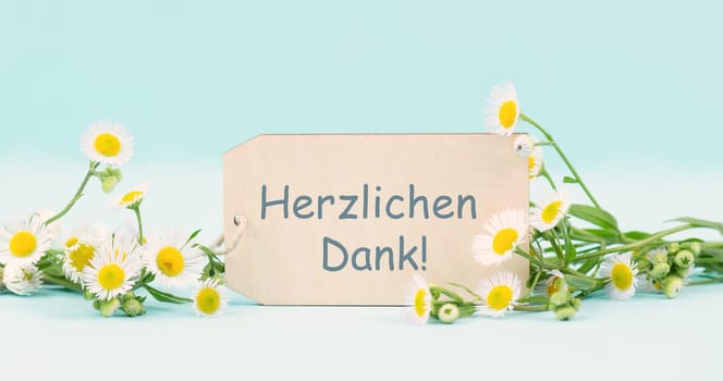 Thank you in german language, card surrounded by flowers, being thankful, support, help and charity concept, positive attitude