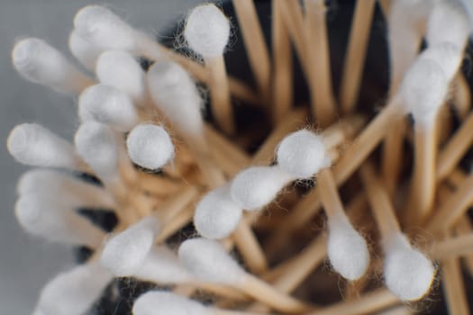 View from above of disposable white cotton buds with beige stick lying in container. Clean consumable using for eyelash extension procedure, applying lash adhesive and gently separating cilia.