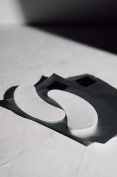 White disposable eyelash extension patches for insulating lashes, applied on lower eyelids in process of procedure lying on black wrapping on clean desk. Vertical.