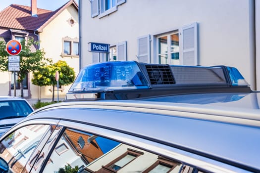 German police car on the street, detail of blue siren flasher. Parking at police station. Translation: Police