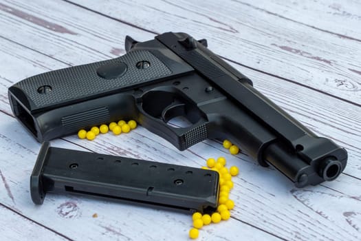 airsoft handgun with yellow bb, on a white wooden background