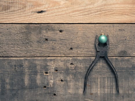 Rusty old pliers with a golden tree shape and Christmas bauble on rustic wood