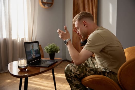 Nervous veteran talking loudly to psychiatrist during therapeutical videoconference via laptop computer