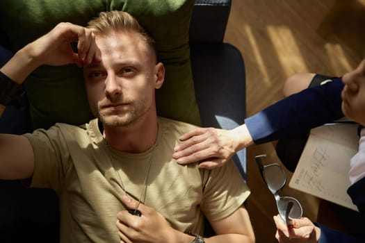 Tired pensive military man feeling worry and despair overhead view. Psychological trauma and PTSD treatment at therapy session