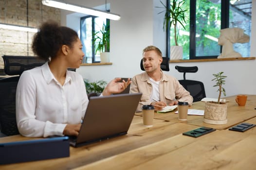 Man and woman coworker talking, discussing ideas and planning marketing strategy together in office