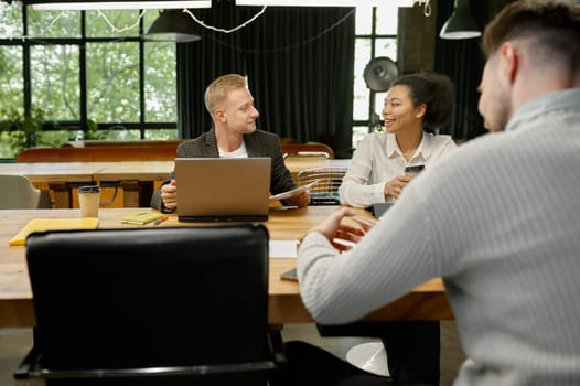 Business people talking and smiling during team meeting in office. Colleagues collaboration concept