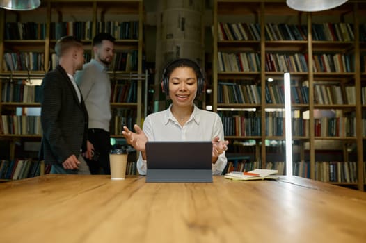 Female office worker wearing headphones working online looking at laptop computer. Watching educational webinar, holding video call with client, virtual meeting with partner concept