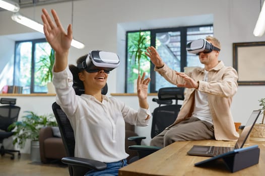 Inspired man and woman coworker wearing vr goggles in office. Male and female colleagues in virtual reality headset playing online games using cyberspace for business meeting and communication