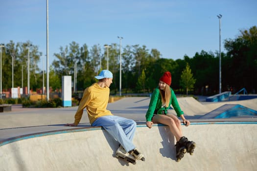 Active positive teenager friends rest after good training in rollerdrom. Young people meeting or dating and sport activity
